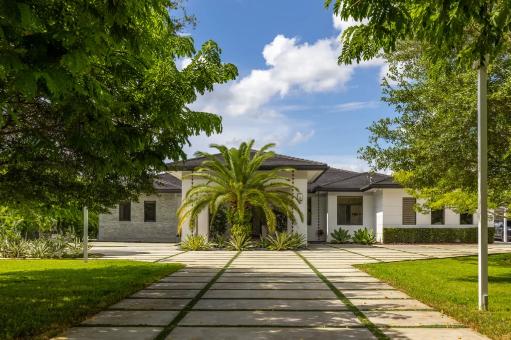 Modern luxury estate in Homestead, FL featuring a long driveway and lush landscaping.