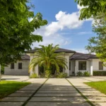Modern luxury estate in Homestead, FL featuring a long driveway and lush landscaping.